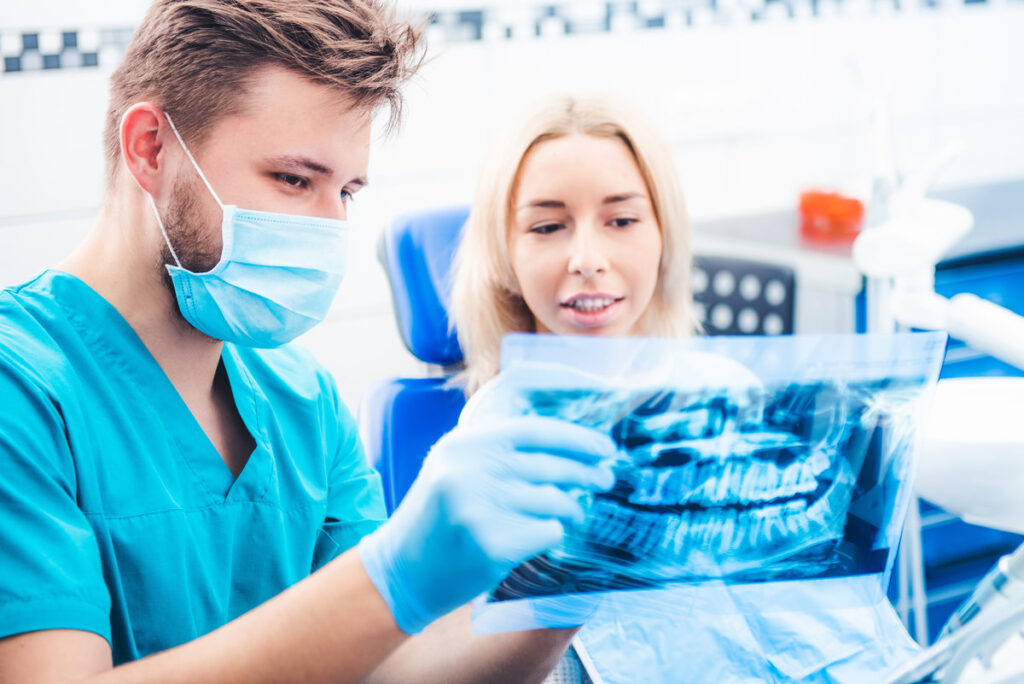 Dentist in mask showing patient dental x-ray