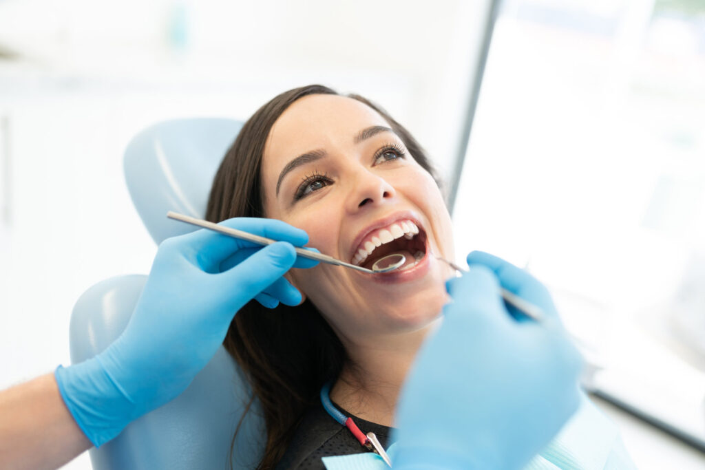 Closeup of dentist examining patient with mirror and carver at clinic