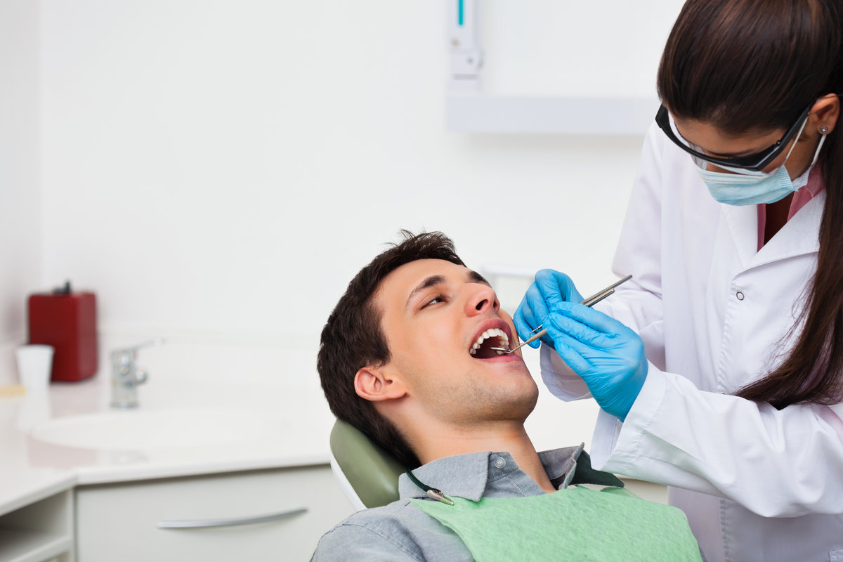 Female dentist examining a male patient at clinic
