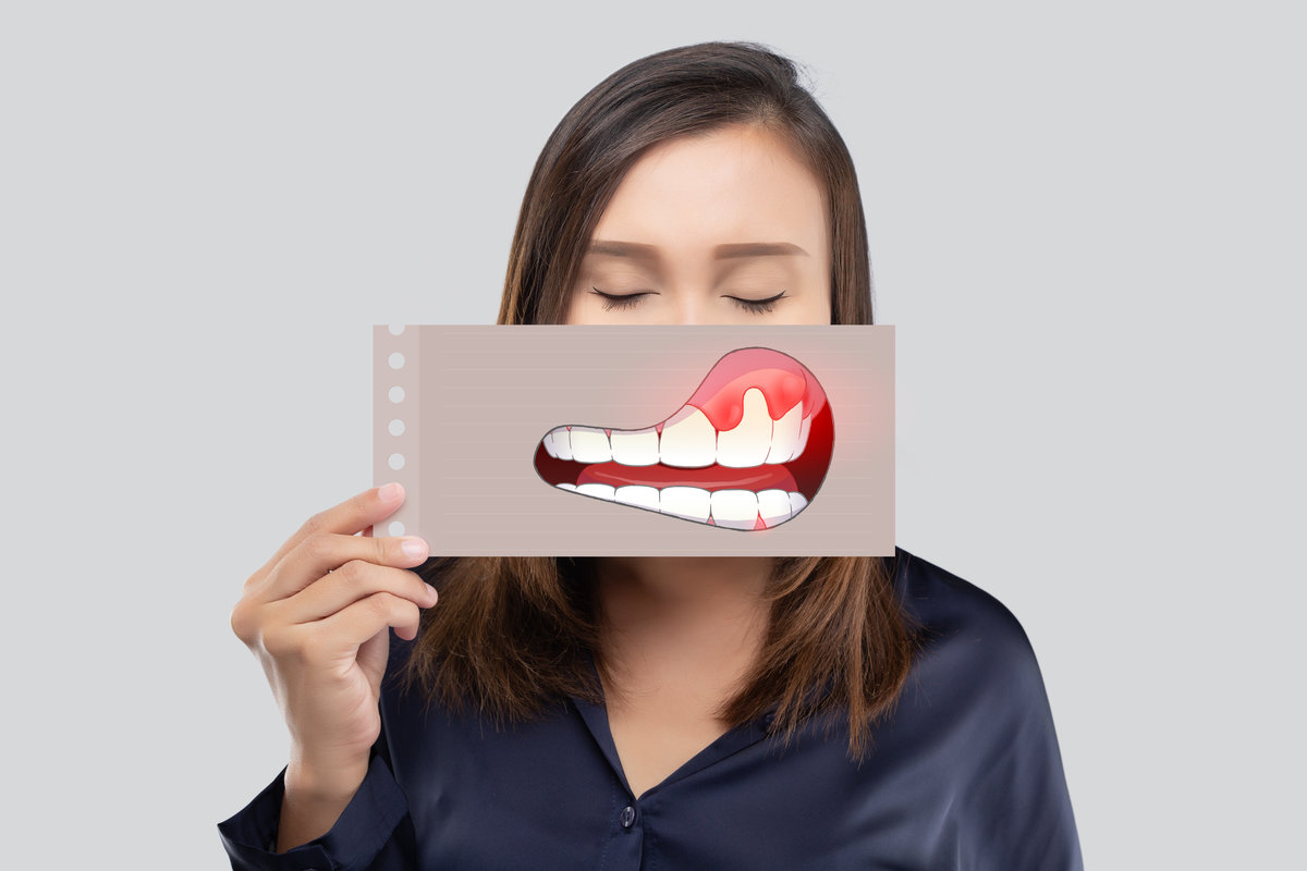 Asian woman in the dark blue shirt holding a paper with the periodontal and gingivitis cartoon picture of his mouth against the gray background, Decayed tooth, The concept with healthcare gums and teeth