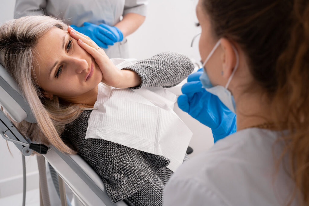 beautiful caucasian girl with toothache sits in a dental chair. Professional dentist helps his female patient in pain.painful treatment help. copy space.
