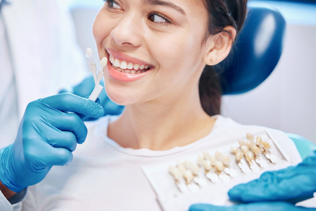 Dentist, woman and dental sample for teeth whitening with choice, decision or implant crown of comparison results. Smile, patient and orthodontist with porcelain veneers, colour guide and healthcare.