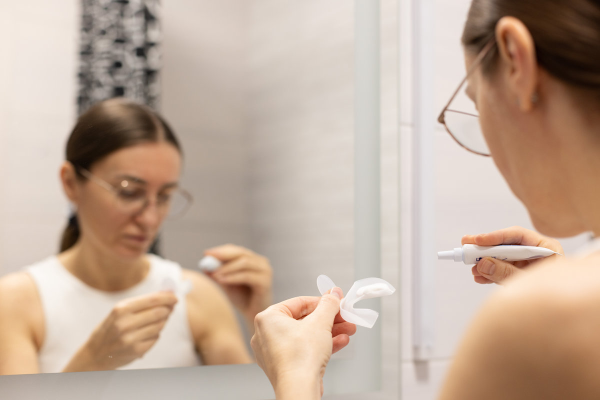 Woman preparing silicon tray for teeth whitening and bleaching gel syringe. Themes dental health, care and beauty. .
