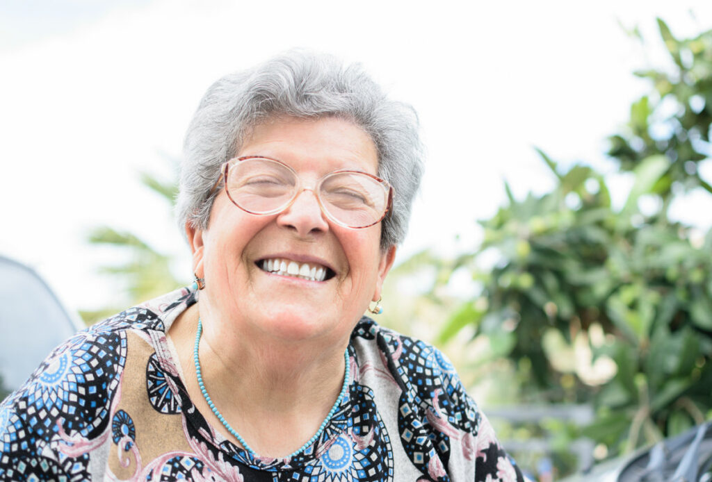 Grandmother with glasses and gray hair very happy smiling while looking at camera with denture