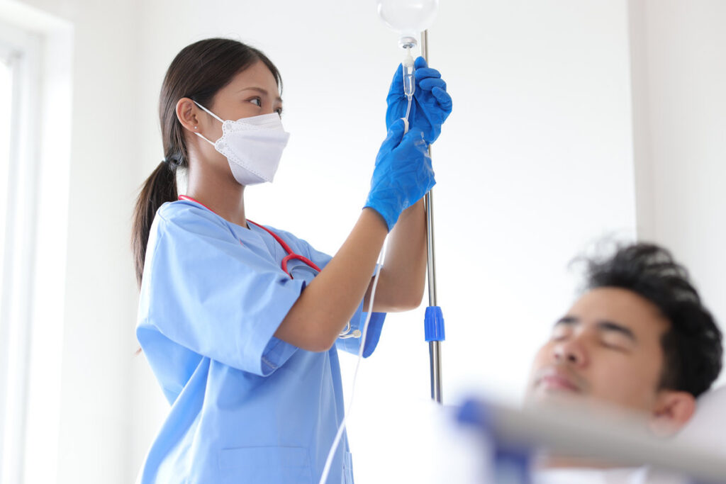 The doctor is taking care and visiting the patient in the hospital. Intern doctor examining a patient's IV line.
