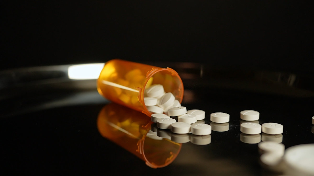 Prescription pill bottle at the table and scatter medications. Opioid crisis in America, narcotic addiction and overdoses by substance abuse.