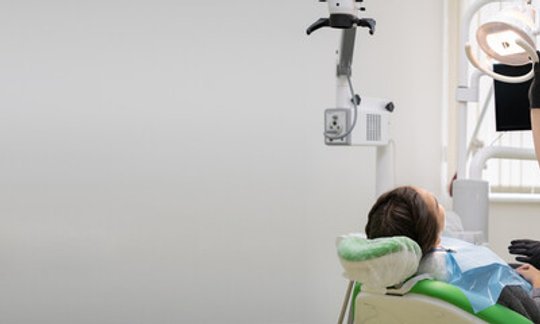 Dentist showing a patient a tooth restoration model in a dental office