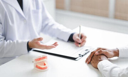 Dentist showing a dental implant model to a patient during a consultation