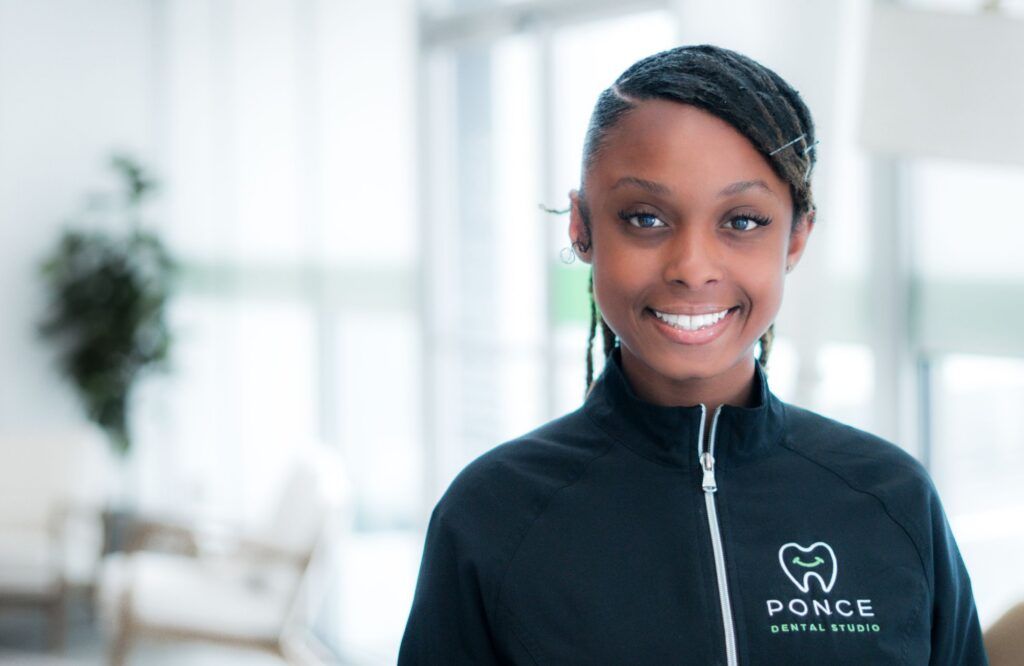 Makayla, Ponce Dental Studio staff member in branded black jacket, modern dental office