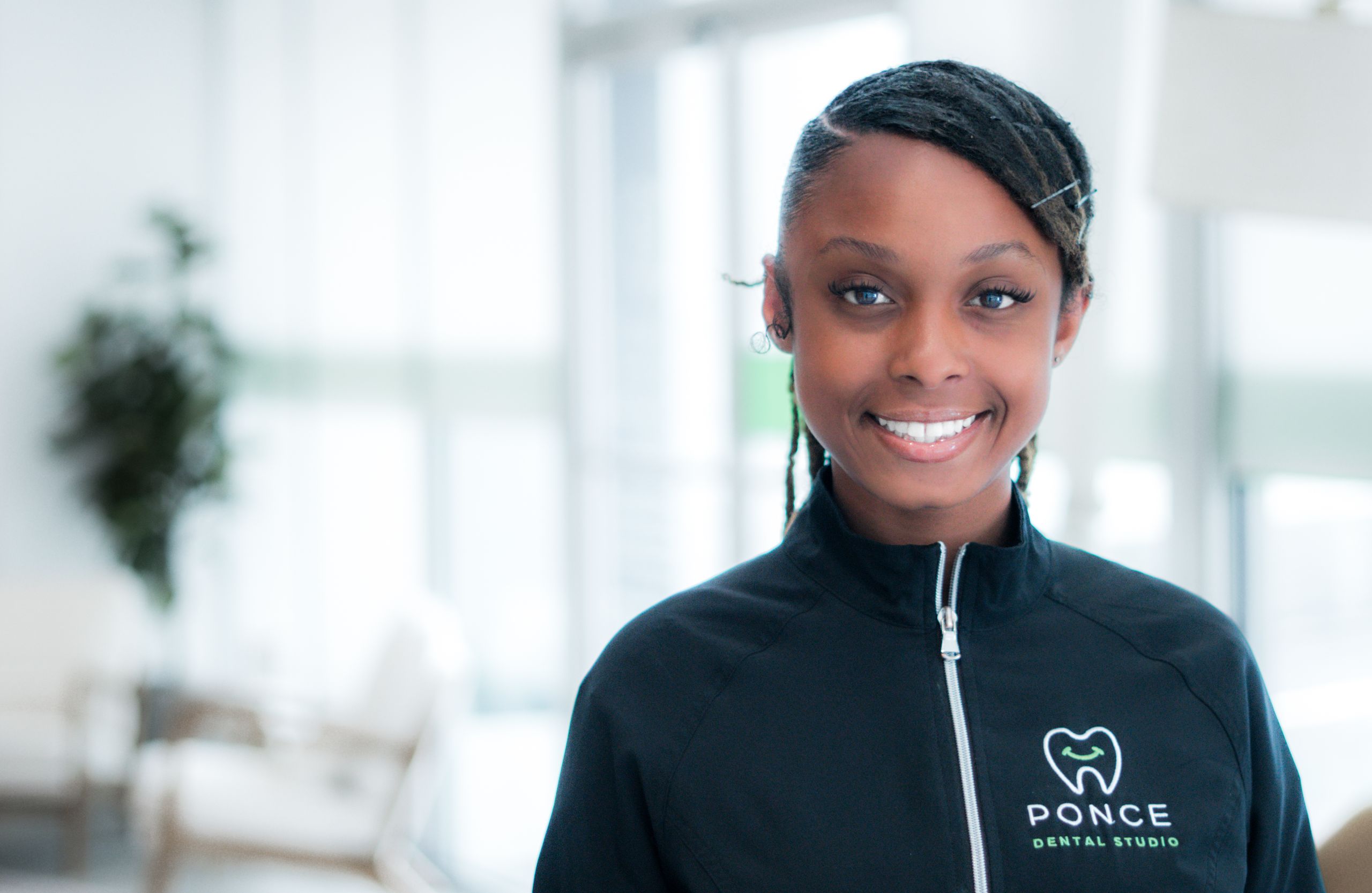 Makayla, Ponce Dental Studio staff member in branded black jacket, modern dental office