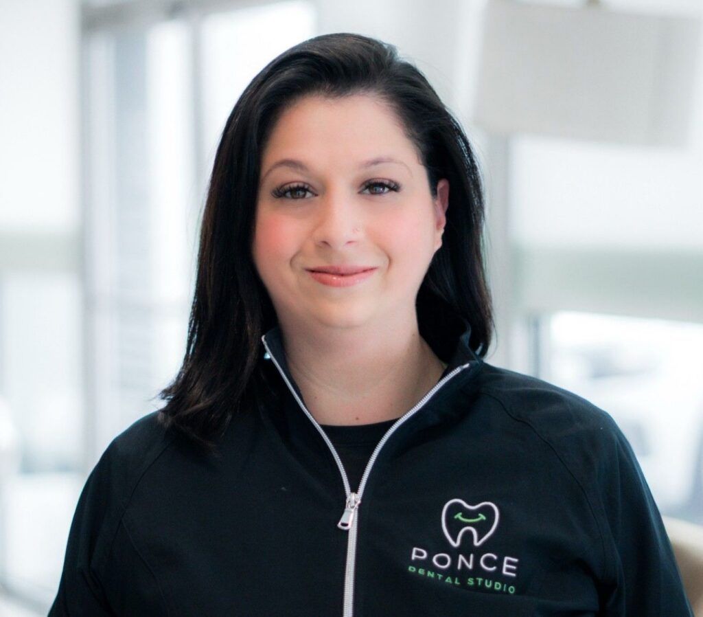 Rachael, Ponce Dental Studio team member in branded black jacket with logo, indoor office