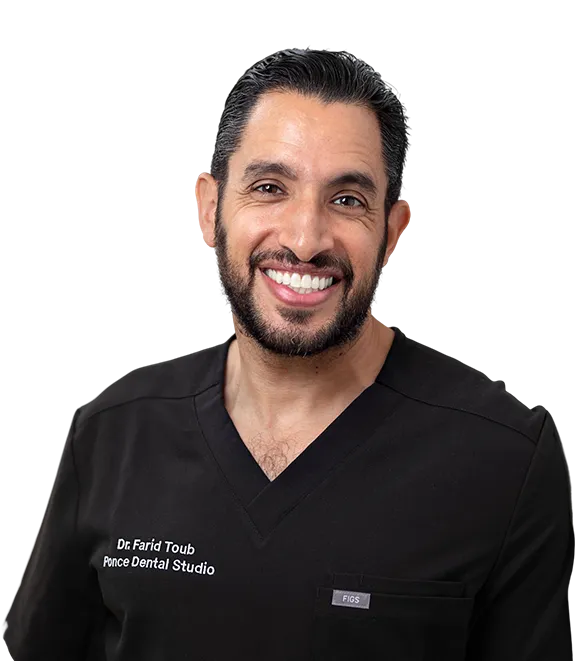 Dr. Farid Toub from Ponce Dental Studio, male dentist in black scrubs, smiling at camera
